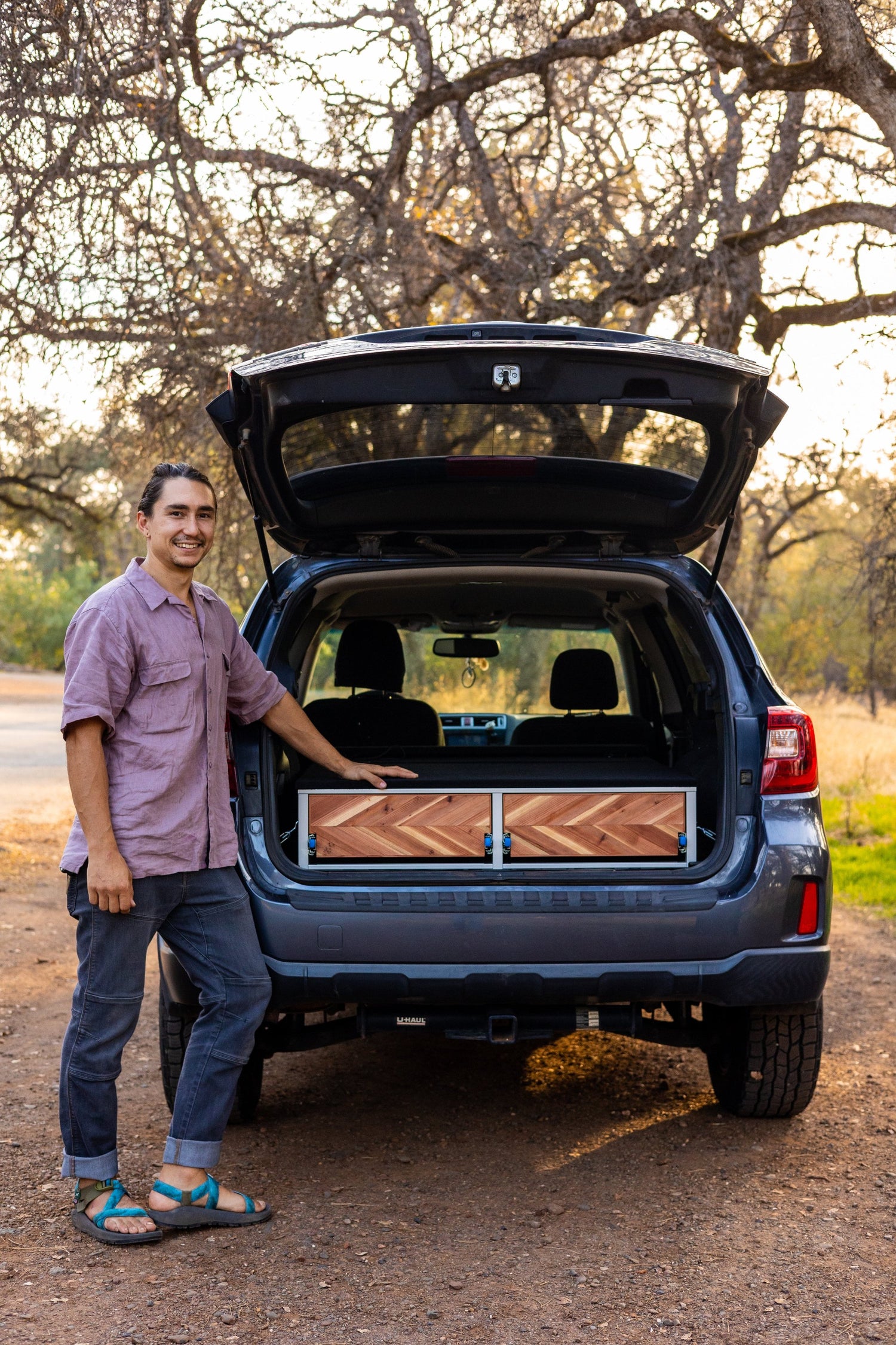 owner person standing in front of compass camper conversion kit in the forest